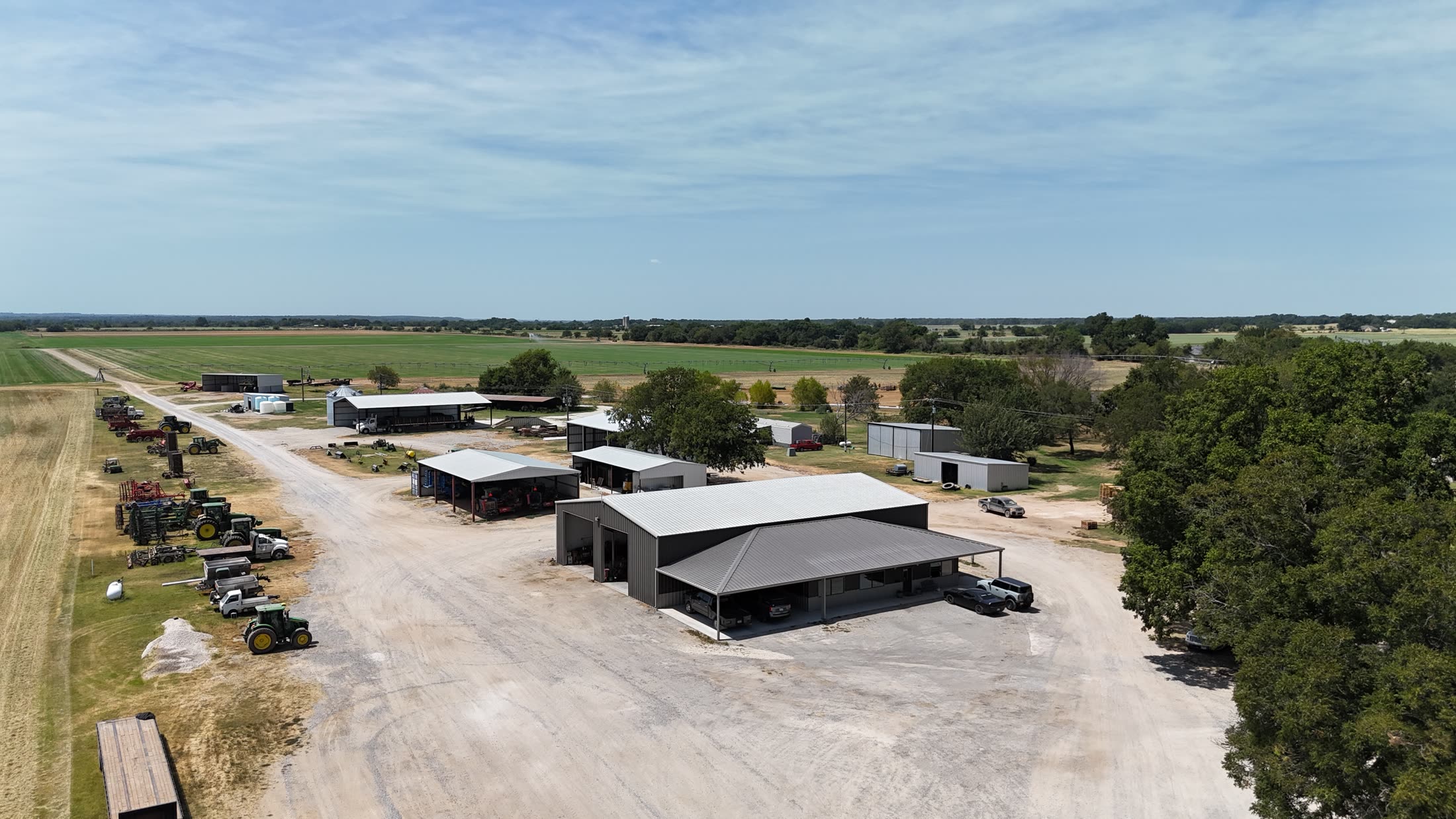 Aerial view of the farm headquarters: equipment barns, tractors, and fields beyond
