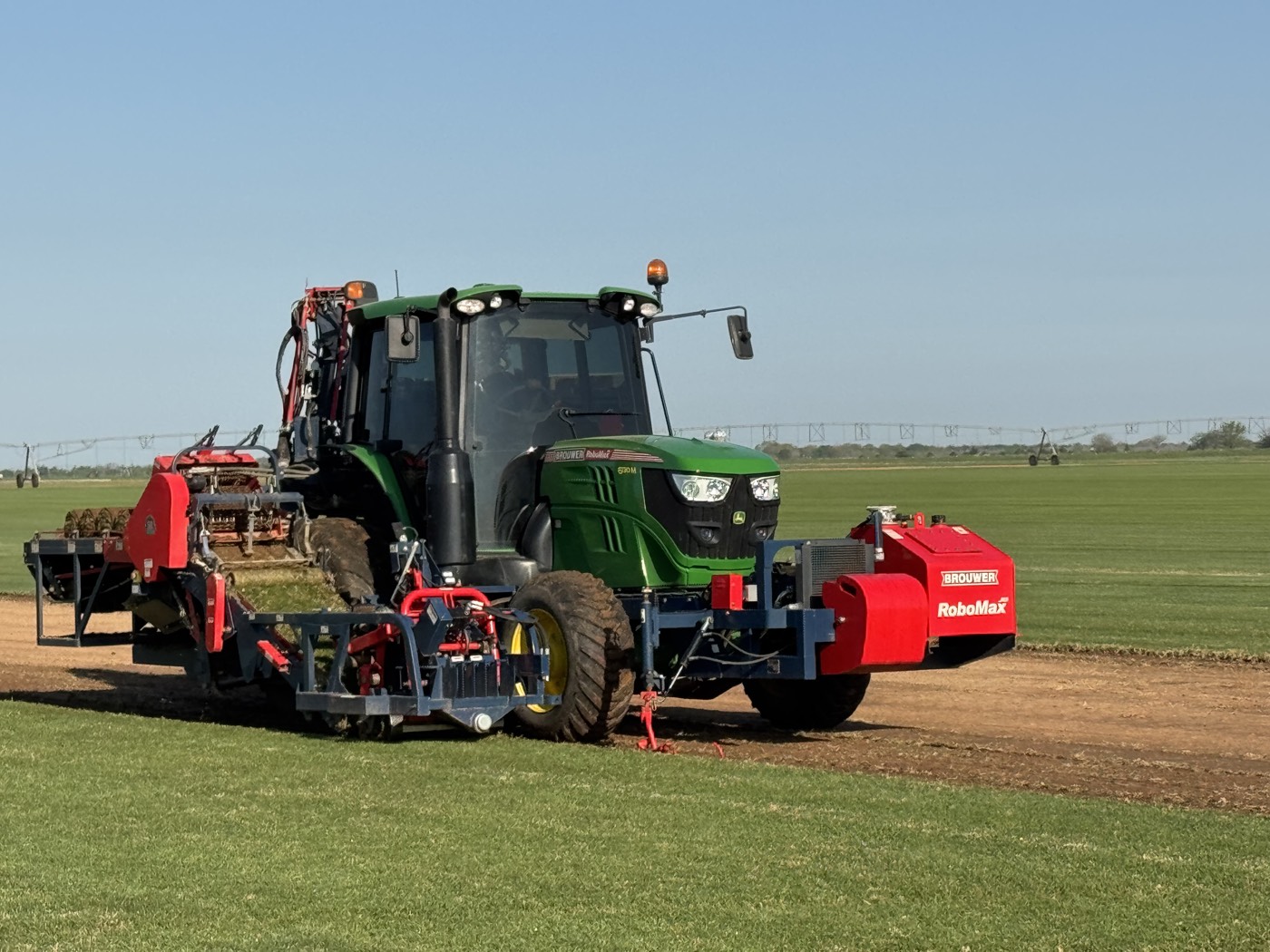 Tractor pulling a Brouwer RoboMax sod harvester across the field
