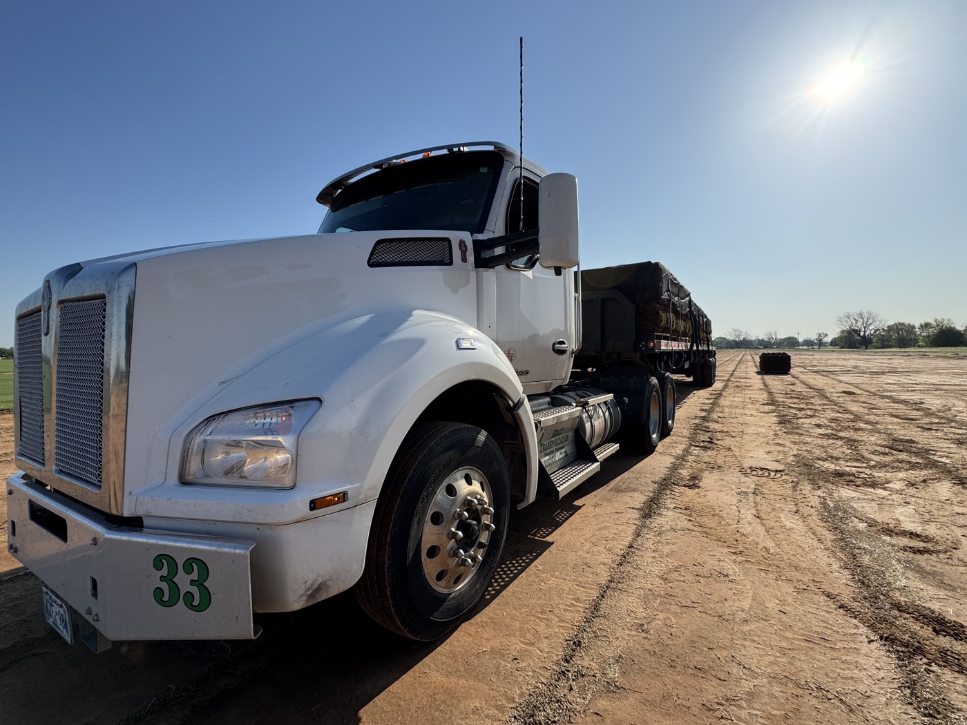 Sod truck number 33 waiting on the field under morning sun